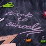 An arrangement of school supplies with 'back to school' written on a chalkboard.